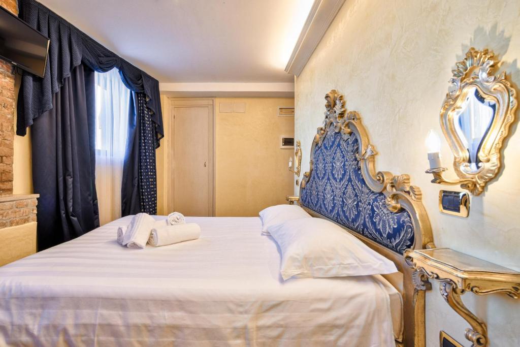 a bedroom with a blue and white bed with a mirror at Hotel Vecellio Venice on the Lagoon in Venice