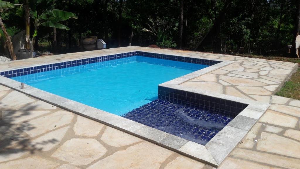 uma piscina com piso de pedra e água azul em Casa Da Lua em Pirenópolis