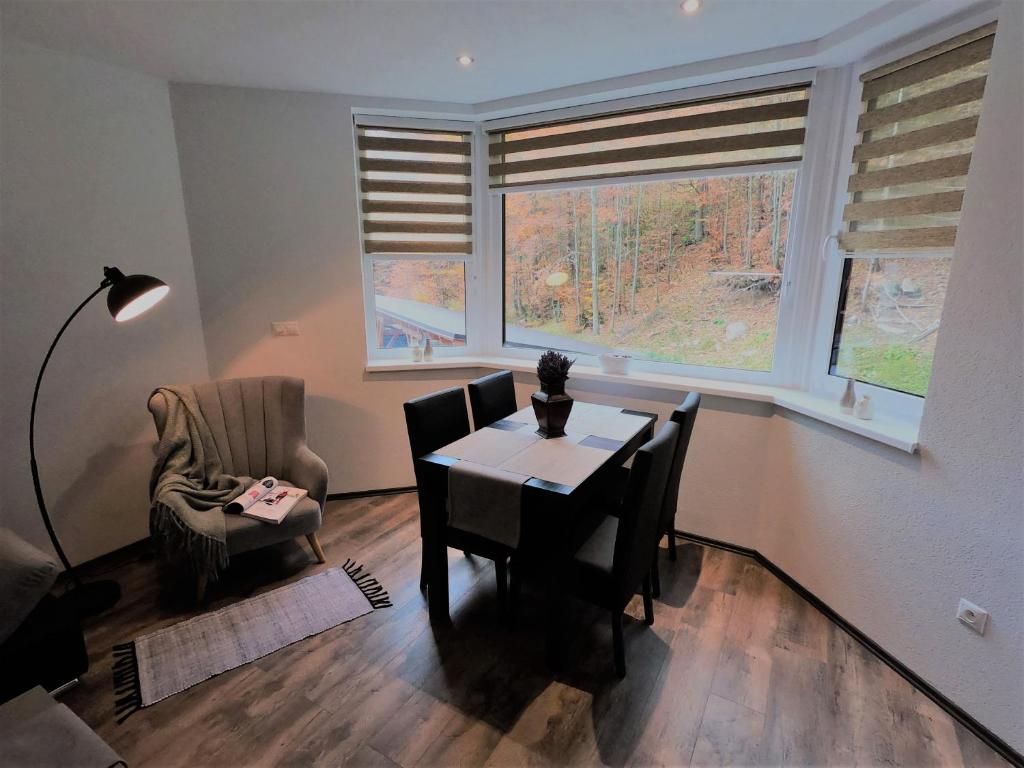 a dining room with a table and chairs and two windows at Apartmán RMNTK Chopok Juh in Horná Lehota