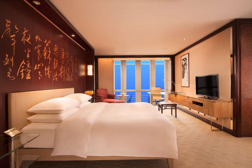 上海的住宿－上海金茂君悅大酒店，卧室配有一张白色大床和电视。