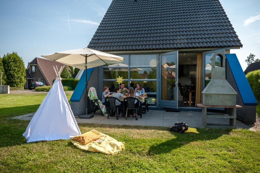 a group of people sitting at a table outside of a house at Hebrechthuis in Vlagtwedde