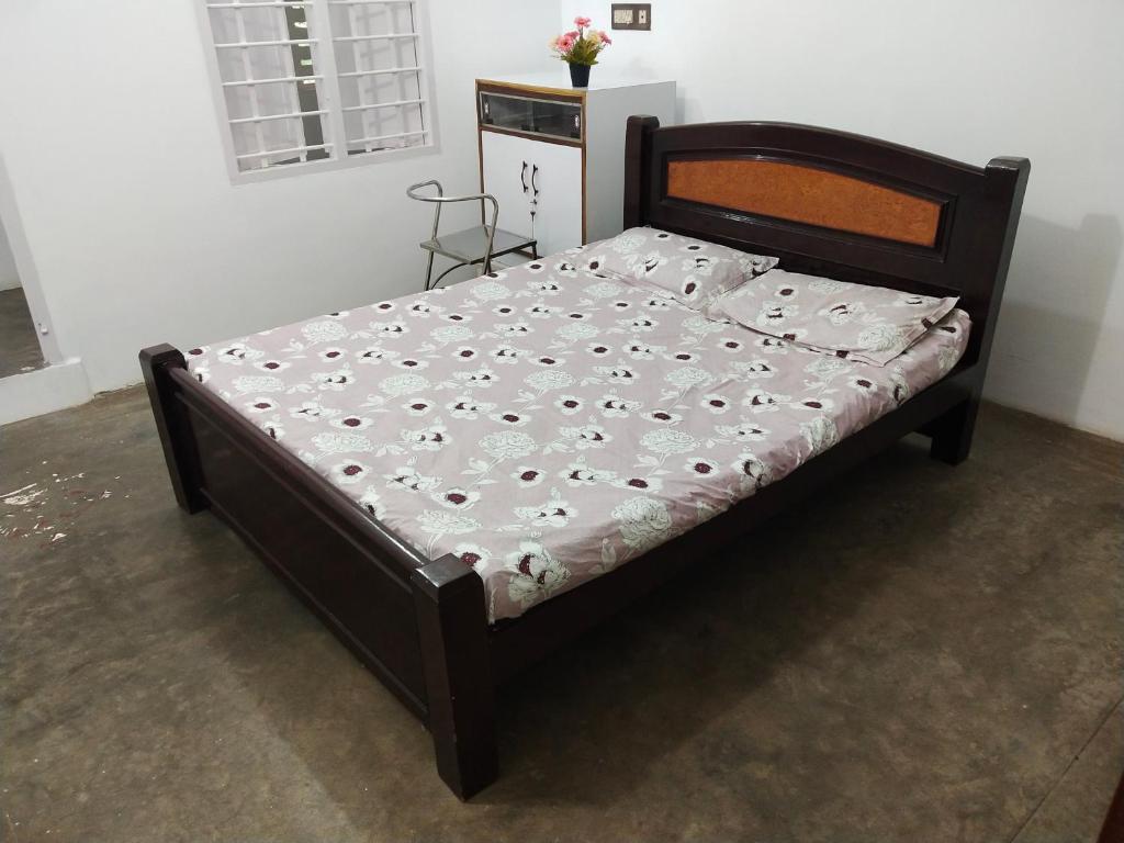 łóżko z drewnianą ramą w sypialni w obiekcie Mayurapriya Inn w mieście Ćennaj