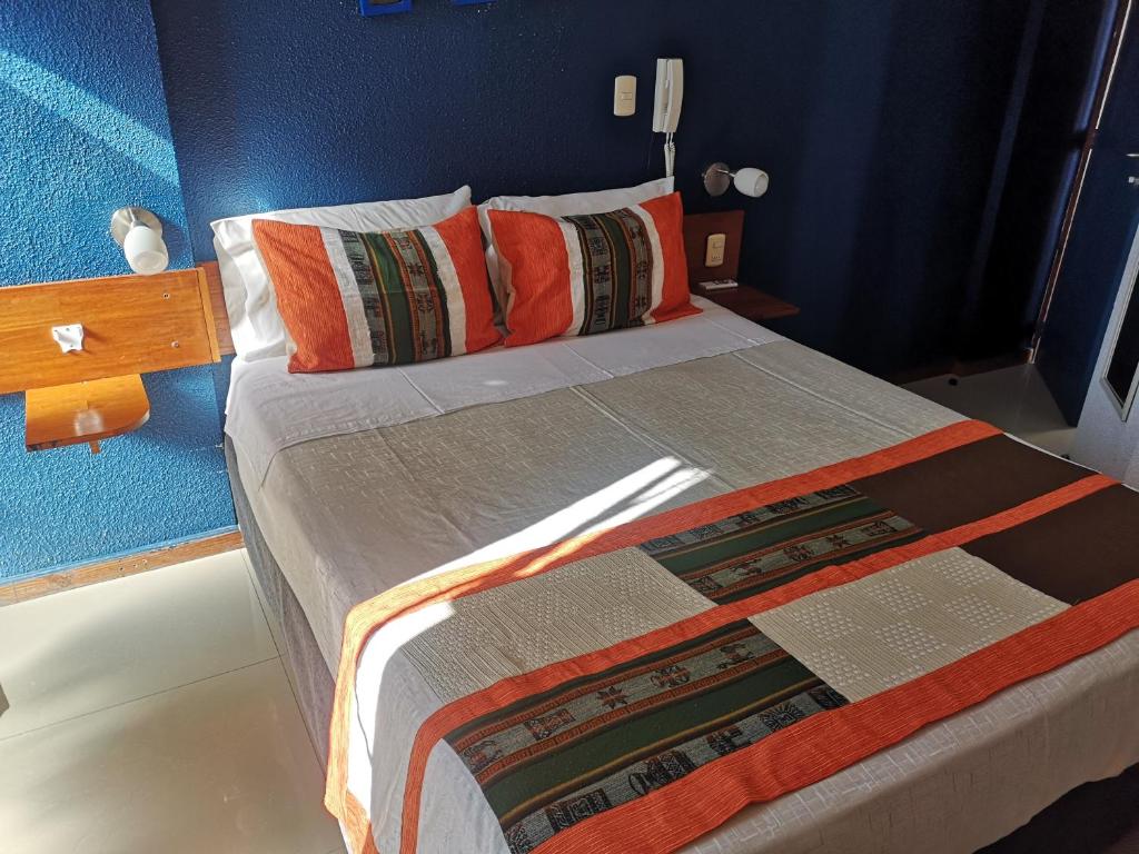 a bedroom with a large bed with orange pillows at Hotel Esmeralda in Iquique