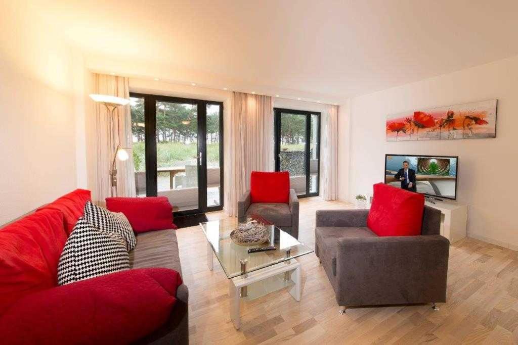 ein Wohnzimmer mit einem roten Sofa und roten Stühlen in der Unterkunft Strandresidenz Appartement Kormoran A07 in Binz