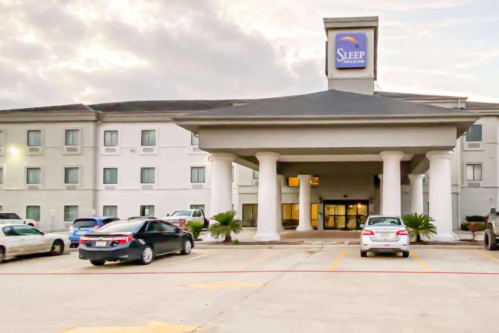 a hotel with cars parked in front of a building at Sleep Inn & Suites Pearland - Houston South in Pearland