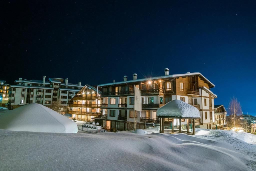 un grand bâtiment dans la neige la nuit dans l'établissement Green Life Bansko, à Bansko