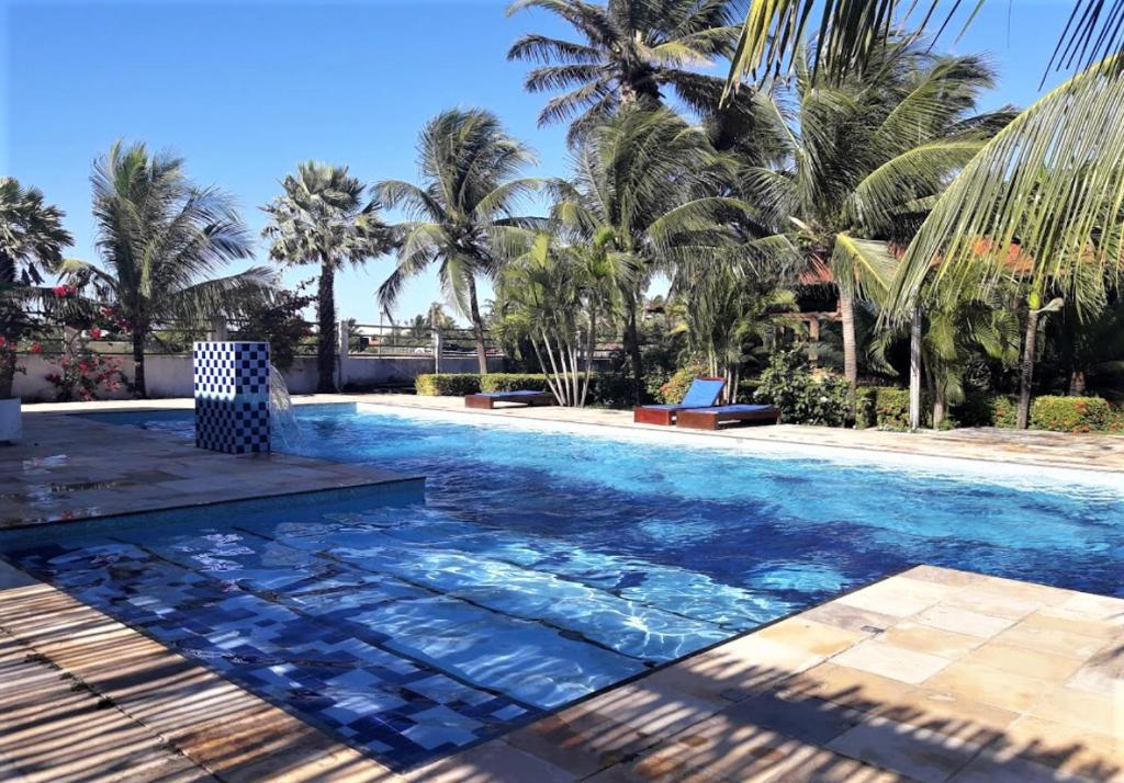 a swimming pool with palm trees in the background at Eco Resort Vento Leste in Jericoacoara