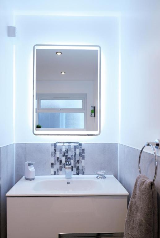 a bathroom with a sink and a mirror at The Duplex Margate with Deck & Living Space Air Conditioning in Margate