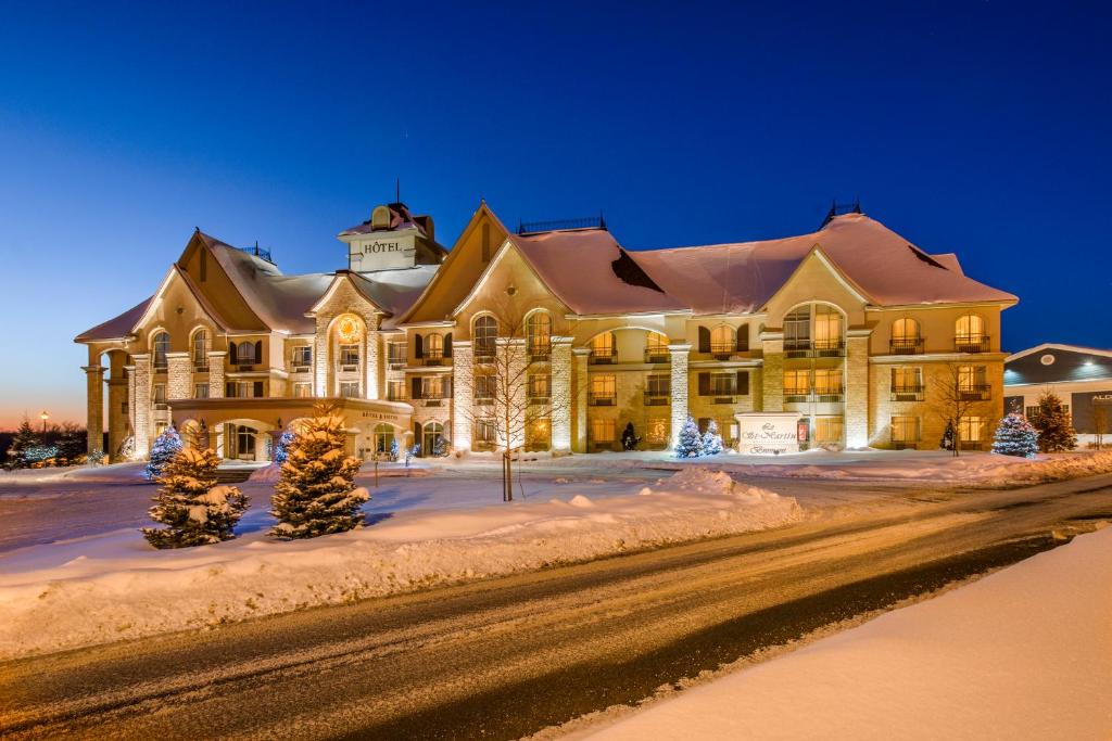 un grand bâtiment dans la neige la nuit dans l'établissement Hotel Vallea Bromont, à Bromont