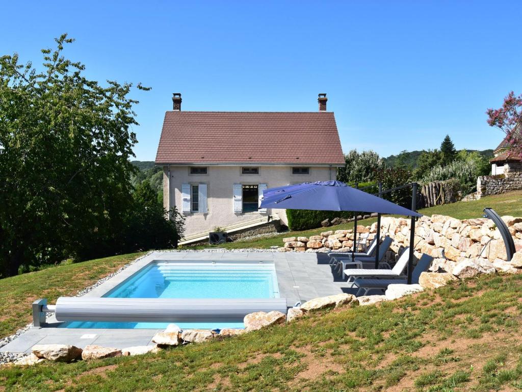 a swimming pool with an umbrella and chairs and a house at Gorgeous Holiday Home in Martigny le Comte with private Pool in Martigny-le-Comte