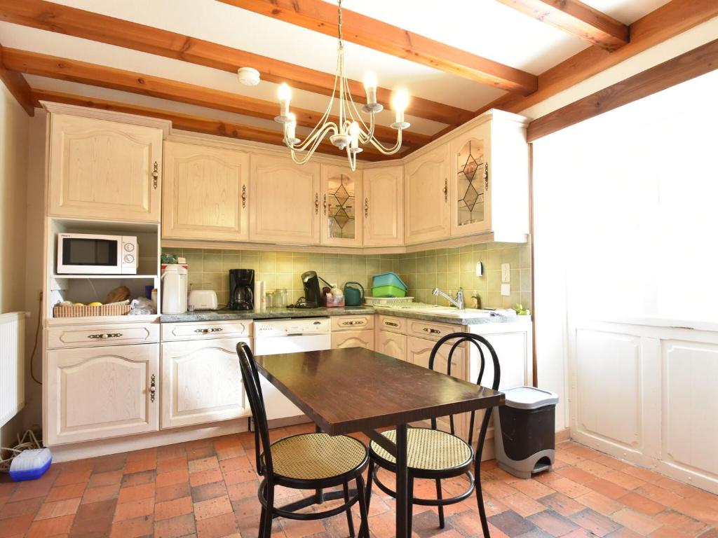 a kitchen with white cabinets and a table and chairs at Gorgeous Holiday Home in Martigny le Comte with private Pool in Martigny-le-Comte