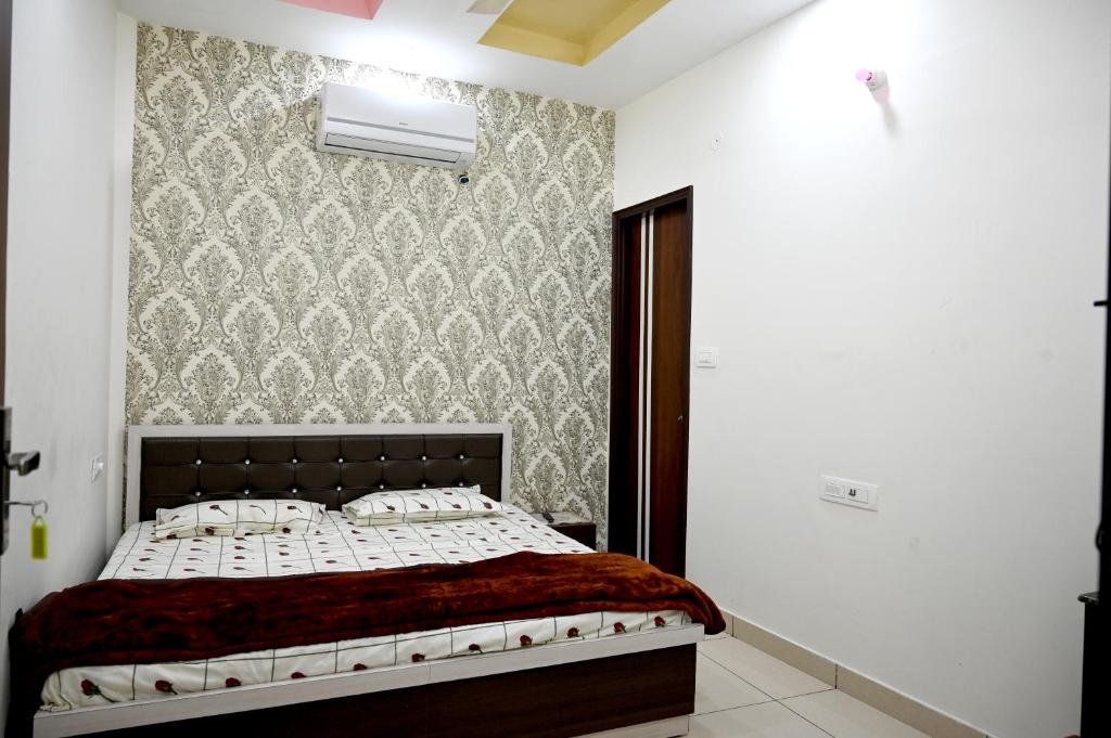 a bedroom with a bed and a wall at No Problem Guest House in Moga