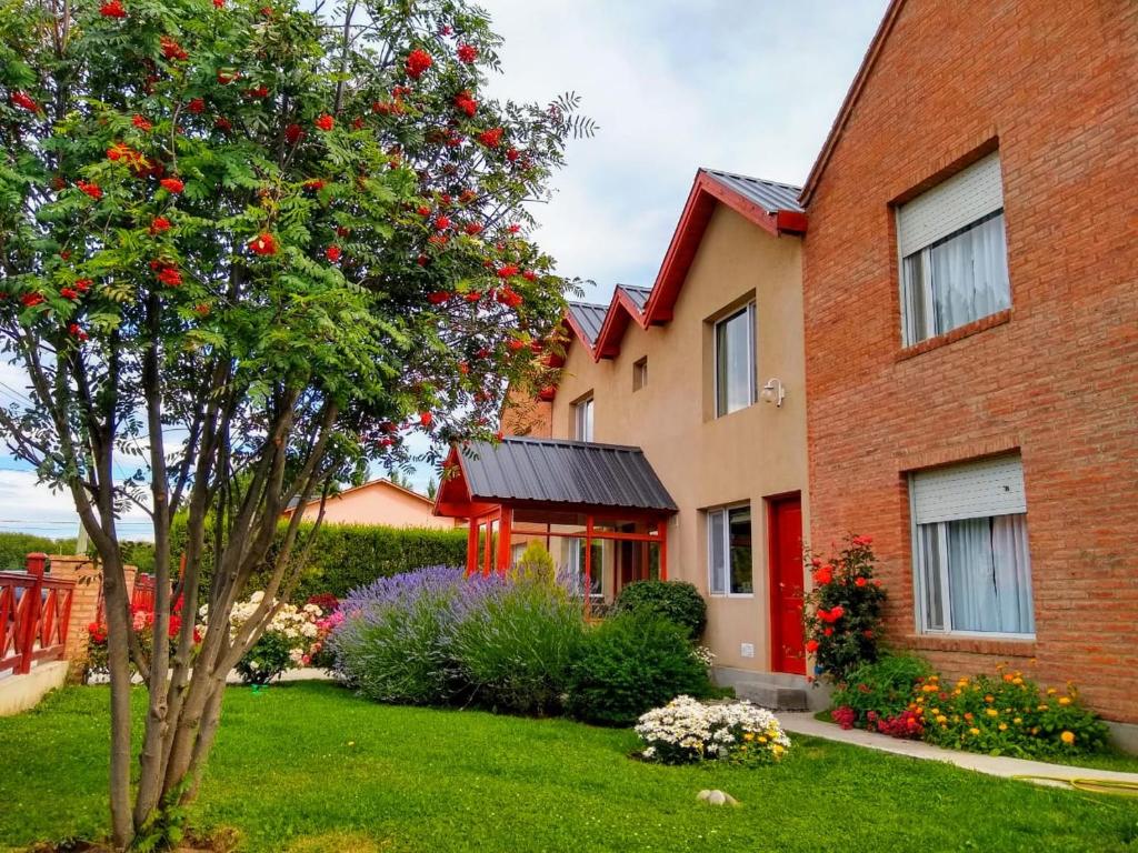 une maison avec un arbre en face d'une cour dans l'établissement Alto Verde Hostería, à El Calafate