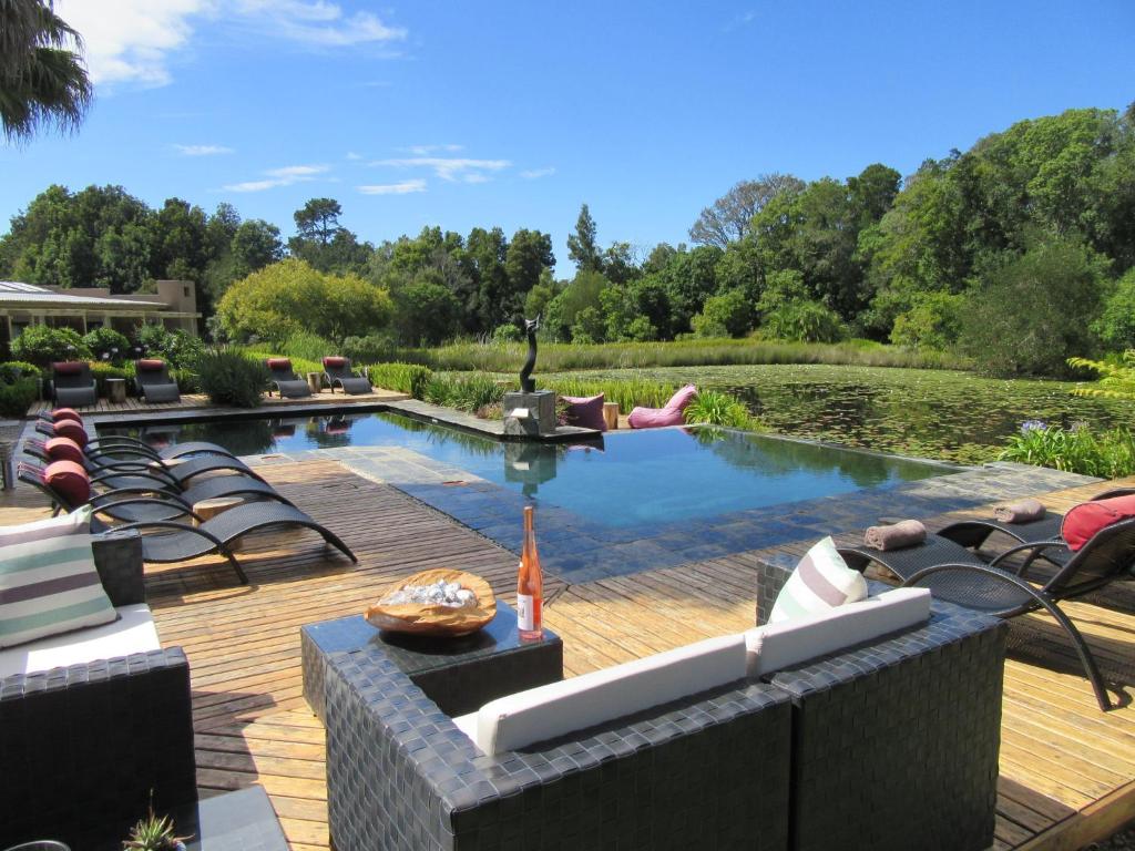 una piscina con tumbonas y un patio con un estanque en Lily Pond Country Lodge en The Crags