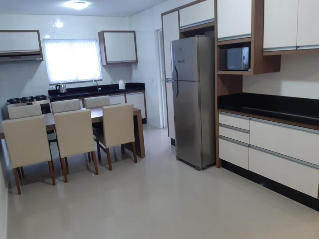 cocina con nevera, mesa y sillas en Apartamento 2 dormitório praia de Bombas, en Bombinhas