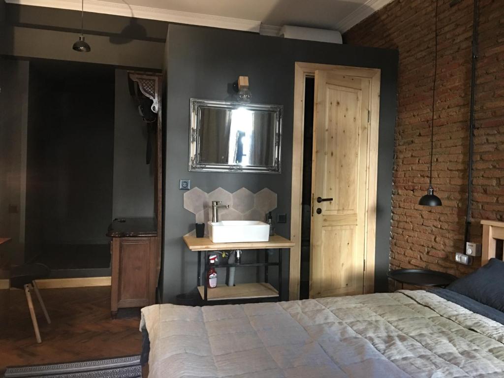 um quarto com uma cama, um lavatório e um espelho em Cozy&stylish Loft em Tbilisi