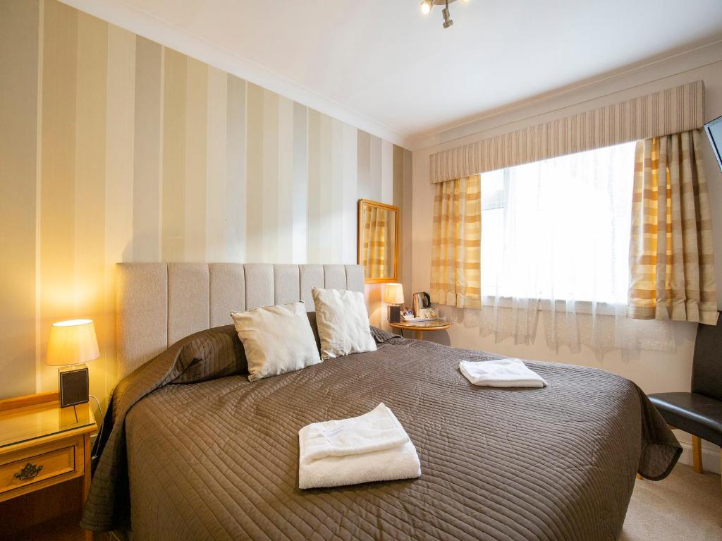 a bedroom with a large bed with two towels on it at OYO Arden Guest House, Craigmillar Castle Edinburgh in Edinburgh
