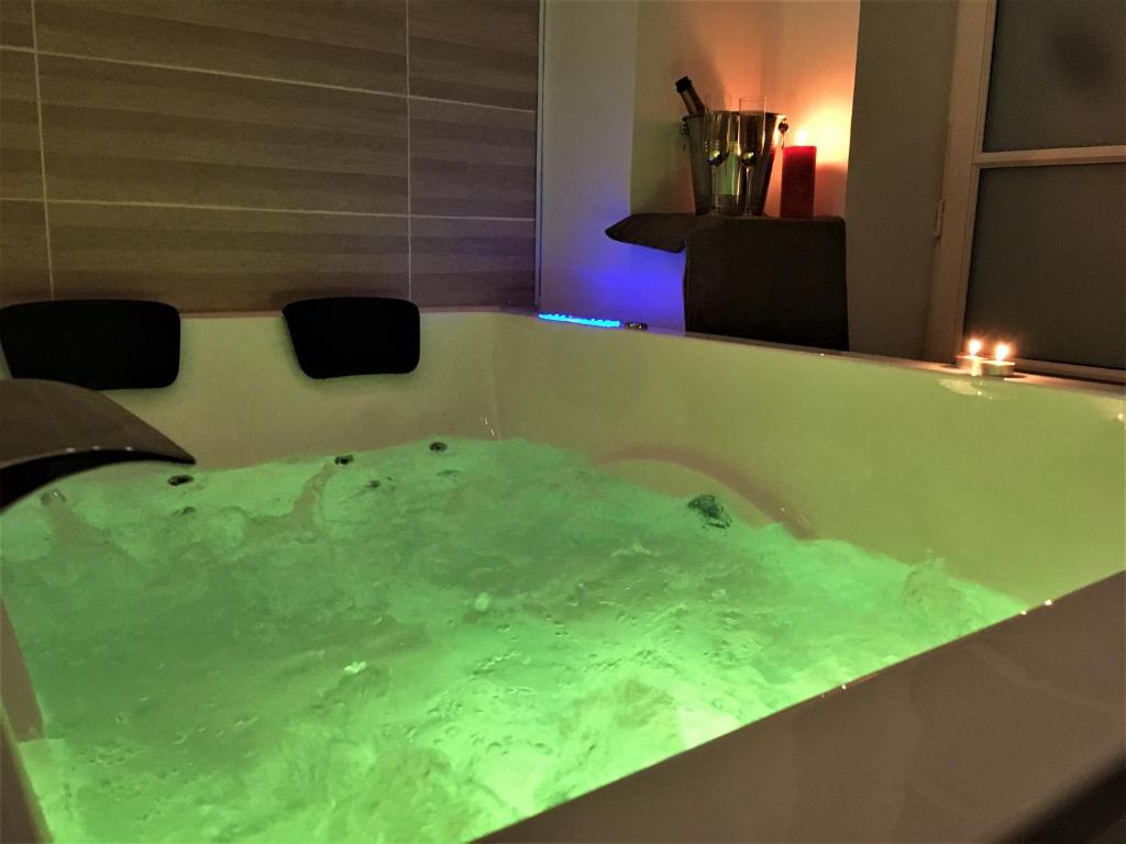 La salle de bains est pourvue d'une baignoire remplie d'eau verte. dans l'établissement GOLD Suite & Spa, à Nantes