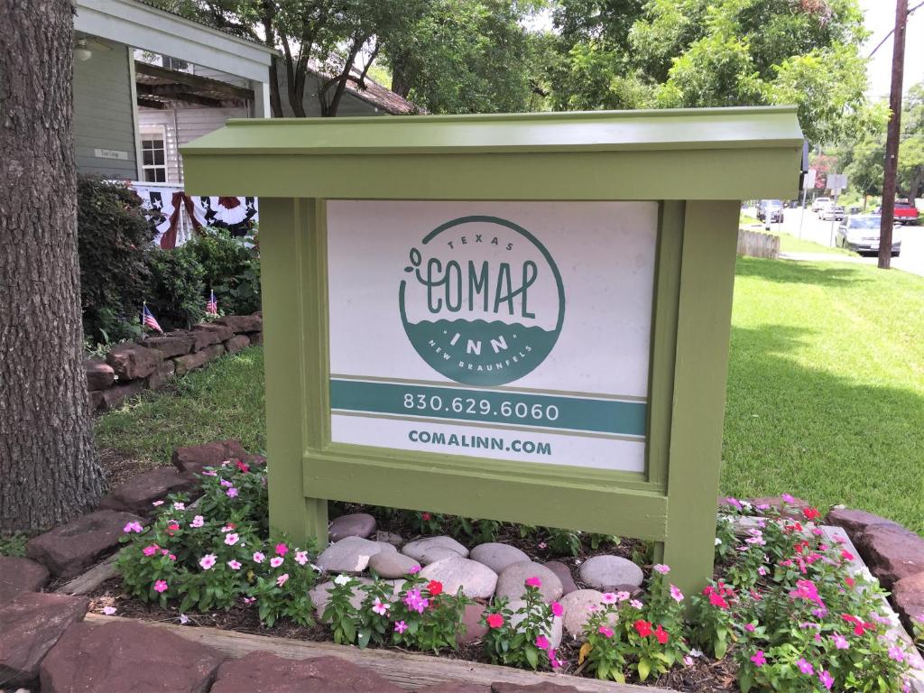 a sign in a flower bed with flowers at Comal Inn in New Braunfels