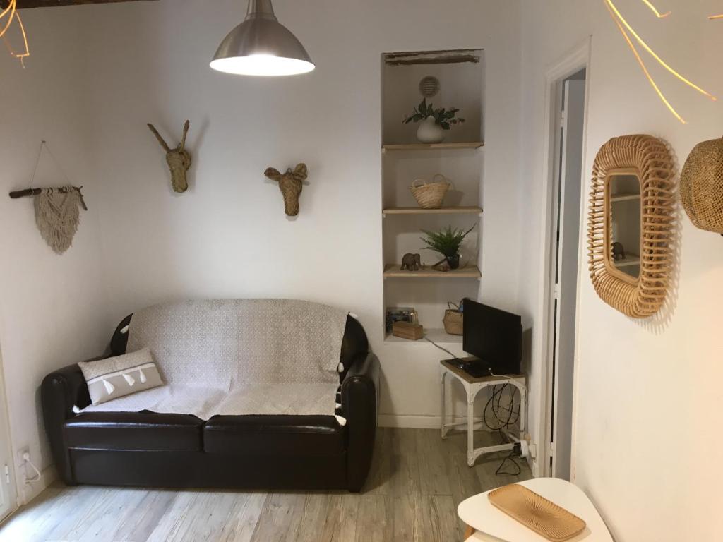 ein Wohnzimmer mit einem Ledersofa und einem TV in der Unterkunft Cassis et ses trésors in Cassis