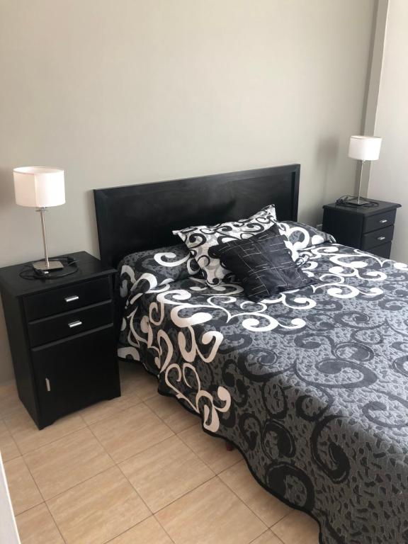 a bedroom with a black and white bed with two lamps at DEPARTAMENTO SANTA FE CON COCHERA gratis in Santa Fe