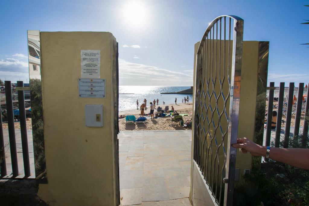 una puerta que conduce a una playa con gente en la playa en La Lajilla Beach Flat, en Arguineguín
