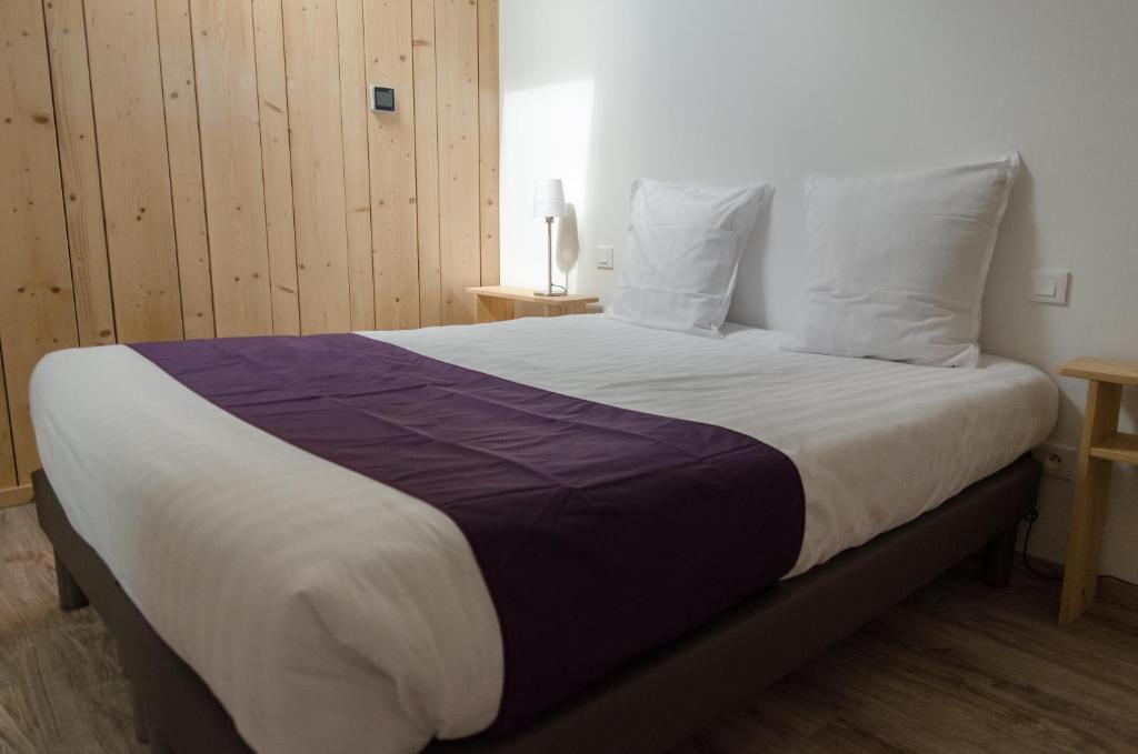 - une chambre dotée d'un grand lit avec des draps violets et blancs dans l'établissement Suites Conviviales la Vignette, à Benfeld