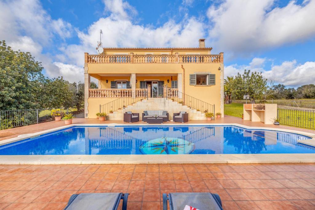 a villa with a swimming pool in front of a house at Can Claret in Caʼs Concos