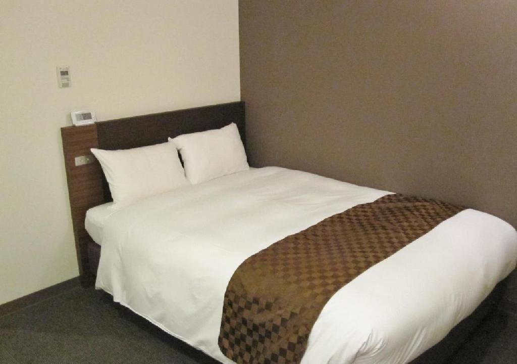 a bedroom with a large bed with white sheets and brown blanket at Hotel Ascent Plaza Hamamatsu / Vacation STAY 64697 in Hamamatsu