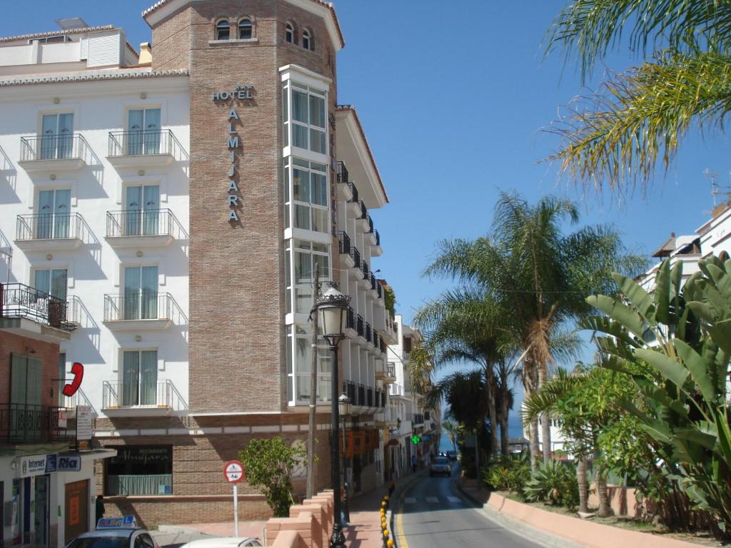 wysoki budynek z wieżą zegarową na ulicy w obiekcie Hotel Almijara - Mares w mieście La Herradura