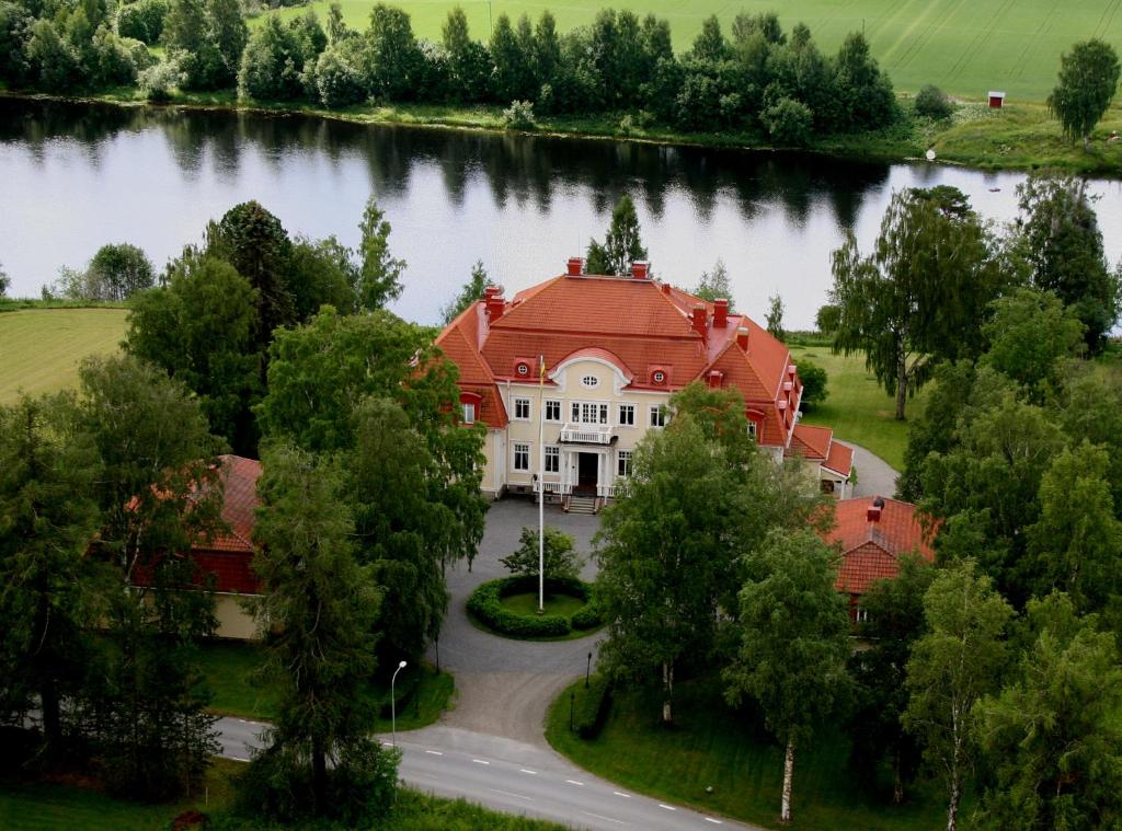 eine Luftansicht eines großen Hauses inmitten eines Sees in der Unterkunft Anno 1908 Torpshammars Herrgård in Torpshammar