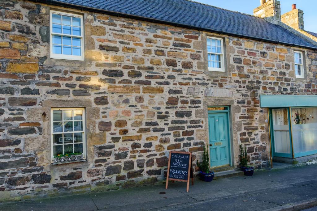 un antiguo edificio de piedra con un cartel delante en Stravaig B&B, en Cullen