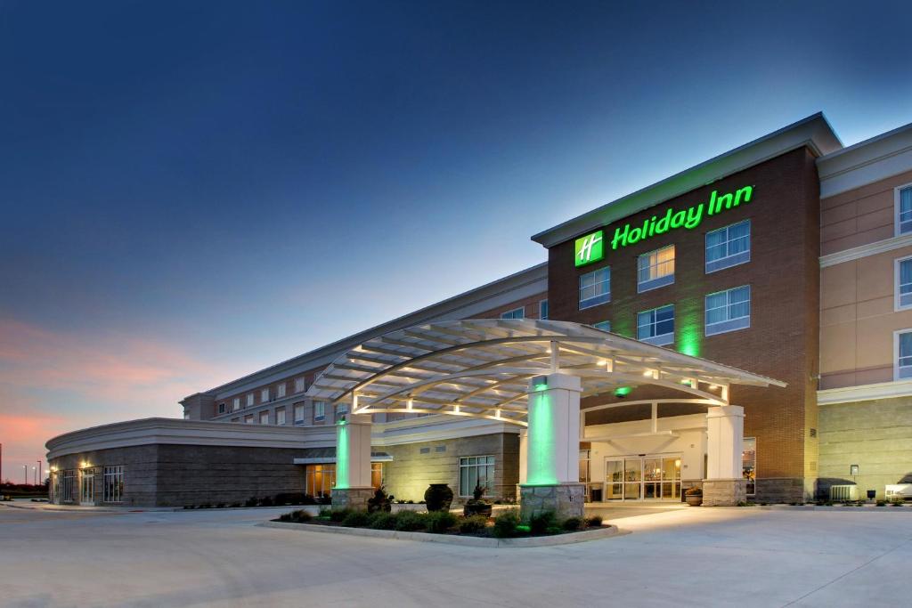 Holiday Inn & Suites Peoria at Grand Prairie, an IHG Hotel في بيوريا: مبنى الفندق مع وجود لافته مكتوب عليها نزل التمريض