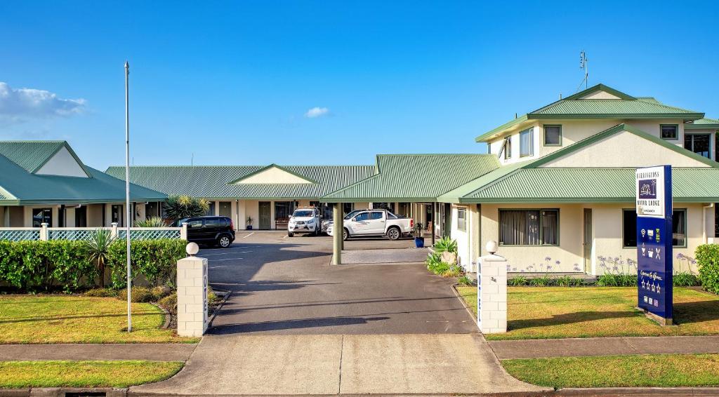 ein Gebäude mit Autos auf einem Parkplatz in der Unterkunft Barringtons Motor Lodge in Whakatane