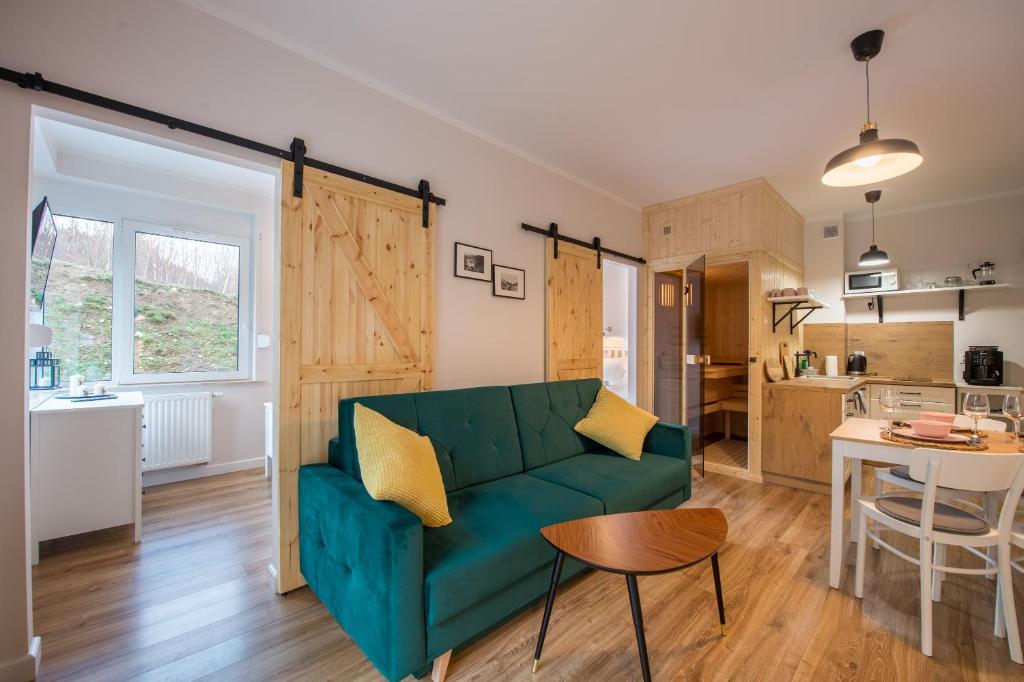 Il comprend un salon avec un canapé vert et une cuisine. dans l'établissement Apartament Tarasowy z SAUNĄ - 5D Apartamenty, à Świeradów-Zdrój