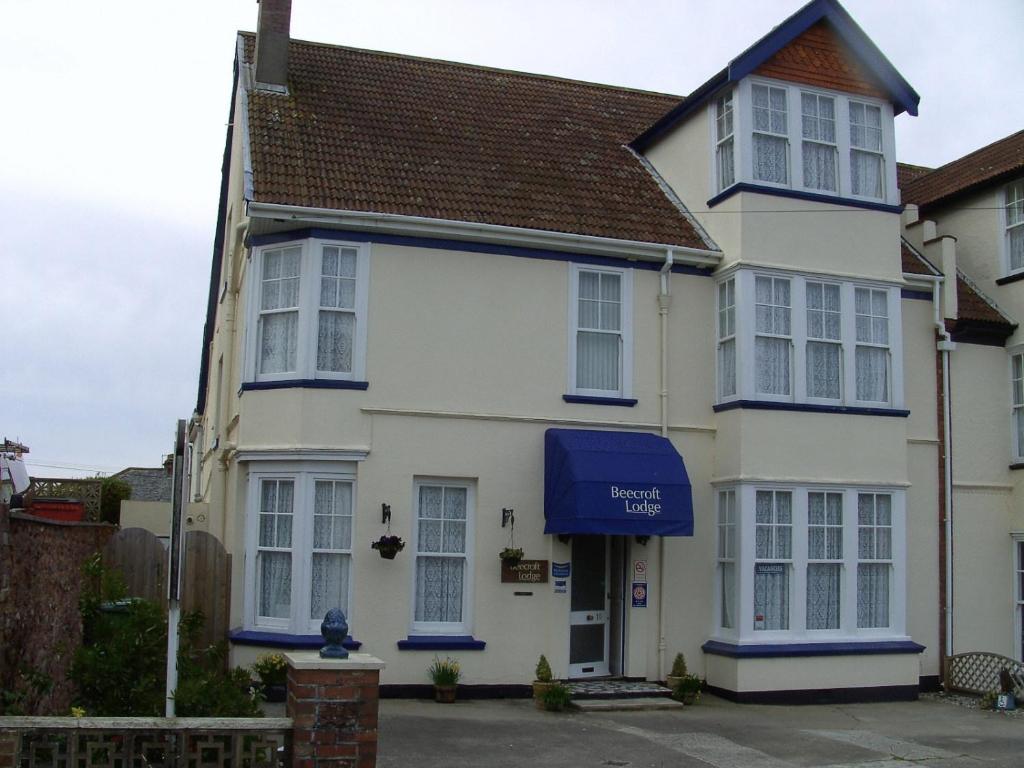 a white house with a blue awning at Beecroft Lodge in Paignton