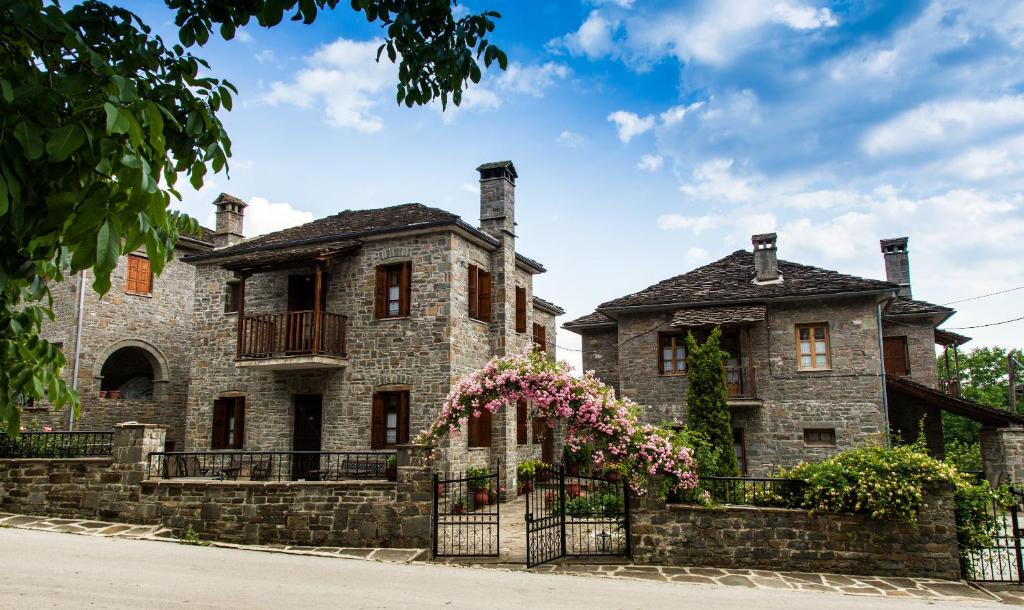 an old stone house with flowers on a fence at Kadi in Tsepelovo