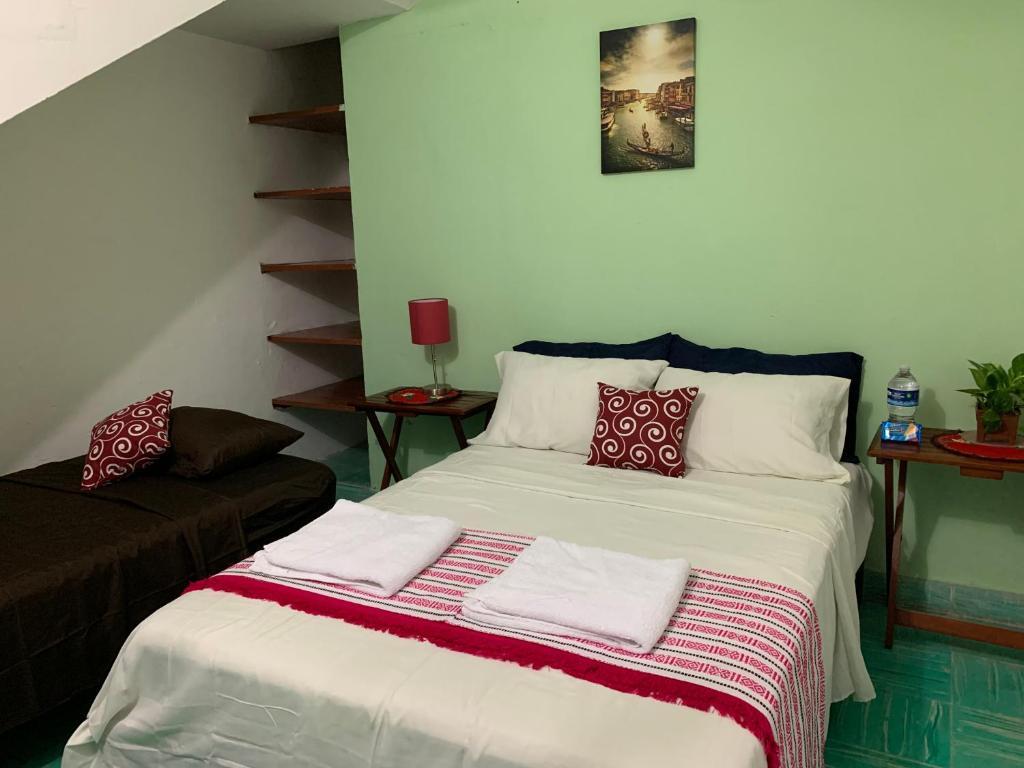 um quarto com uma cama com lençóis brancos e almofadas vermelhas em casa alegria em Mérida