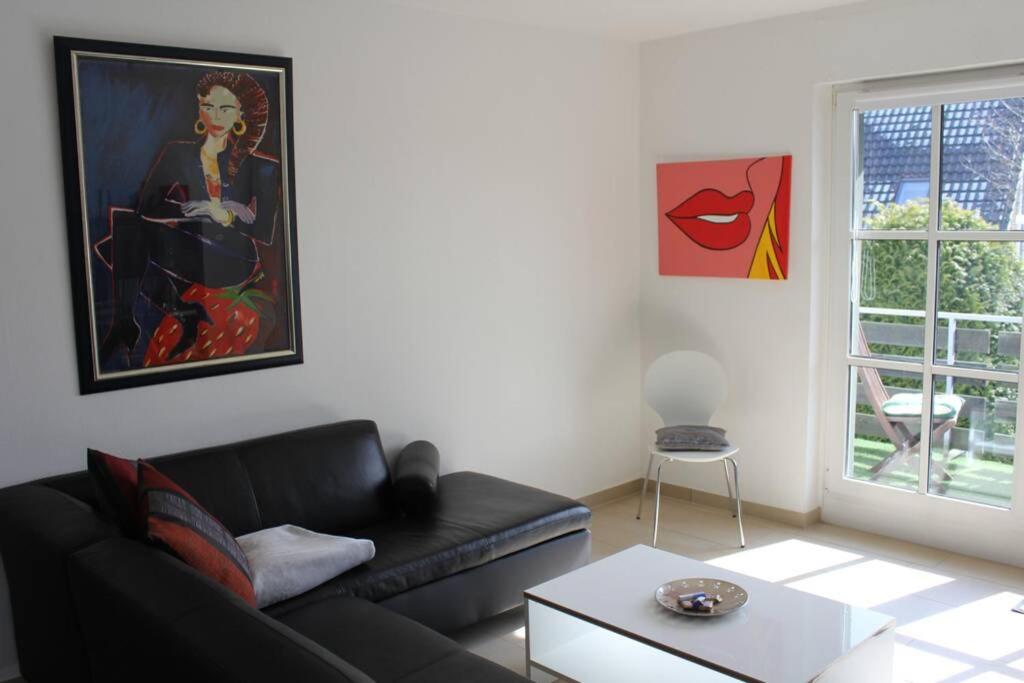 a living room with a black couch and a painting at Große Wohnung 20 km von Köln bis zu 14 Personen in Rösrath