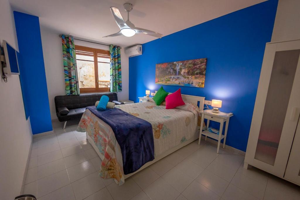 1 dormitorio con paredes azules y 1 cama con almohadas coloridas en Casa Camino al Castillo, en Xàtiva