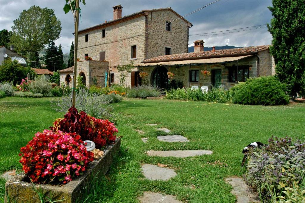 een tuin met een huis en bloemen ervoor bij Holiday Home Il Moro Novo in Cortona