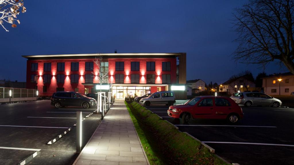 ein rotes Gebäude mit Autos auf einem Parkplatz in der Unterkunft Hotel Wallern Garni in Wallern an der Trattnach