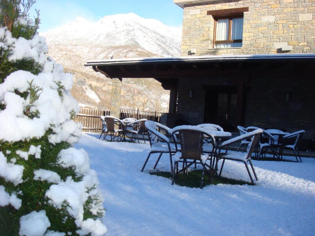 a patio with tables and chairs in the snow at Hotel Sesué in Sesué