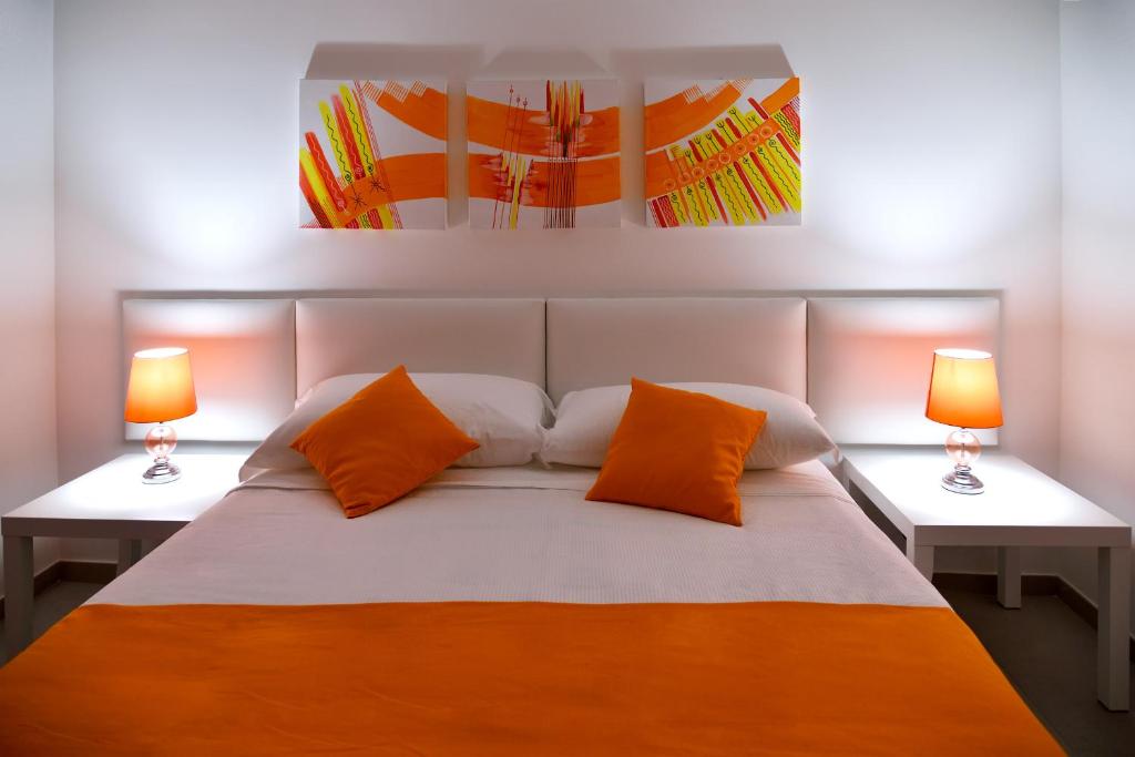a bedroom with an orange and white bed with two lamps at Chapeau Apartment in Pontecagnano