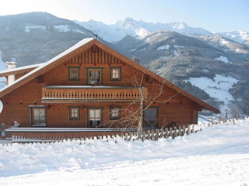 une cabane en rondins dans la neige avec des montagnes en arrière-plan dans l'établissement Bergbauernhof Untermoos, à Taxenbach