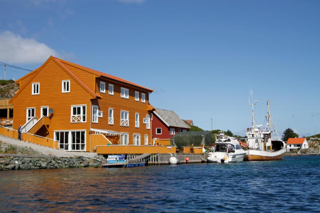 un grande edificio arancione con barche in acqua di Røvær KulturHotell a Røvær