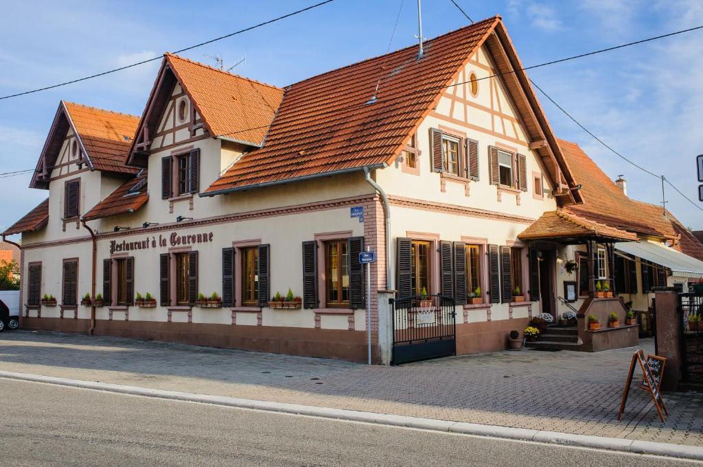 ein weißes Gebäude mit braunem Dach auf einer Straße in der Unterkunft Hôtel Restaurant La Couronne in Roppenheim