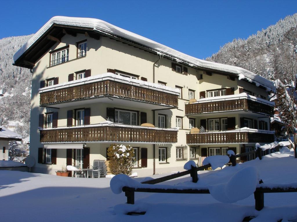 ein großes Gebäude mit Schnee auf dem Boden in der Unterkunft Apartments Trepp in Klosters