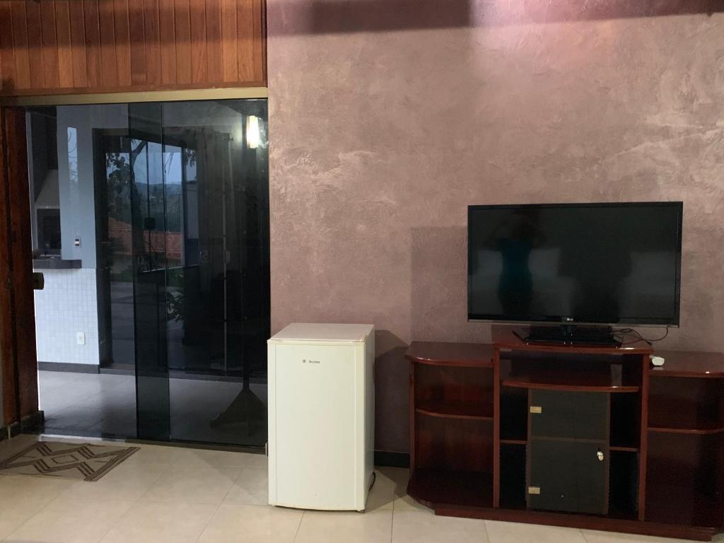 a living room with a flat screen tv and a trash can at Chalés da Zelma in Capitólio