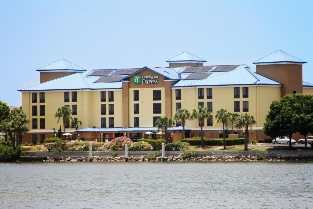 Holiday Inn Express Hotel & Suites Tampa-Rocky Point Island, an IHG Hotel في تامبا: فندق ذو مبنى كبير بجانب تجمع المياه